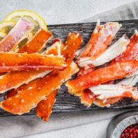 Top view of cooked crab legs on wooden dish.