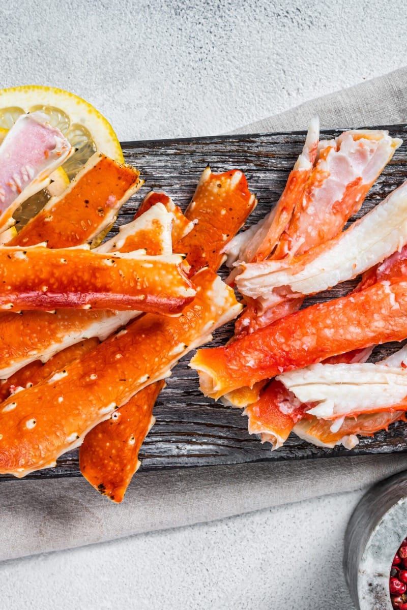 Top view of cooked crab legs on wooden dish.