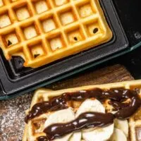 Prepared waffle next to waffle just cooked in waffle maker.