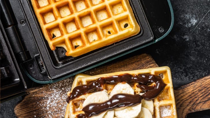 Prepared waffle next to waffle just cooked in waffle maker.