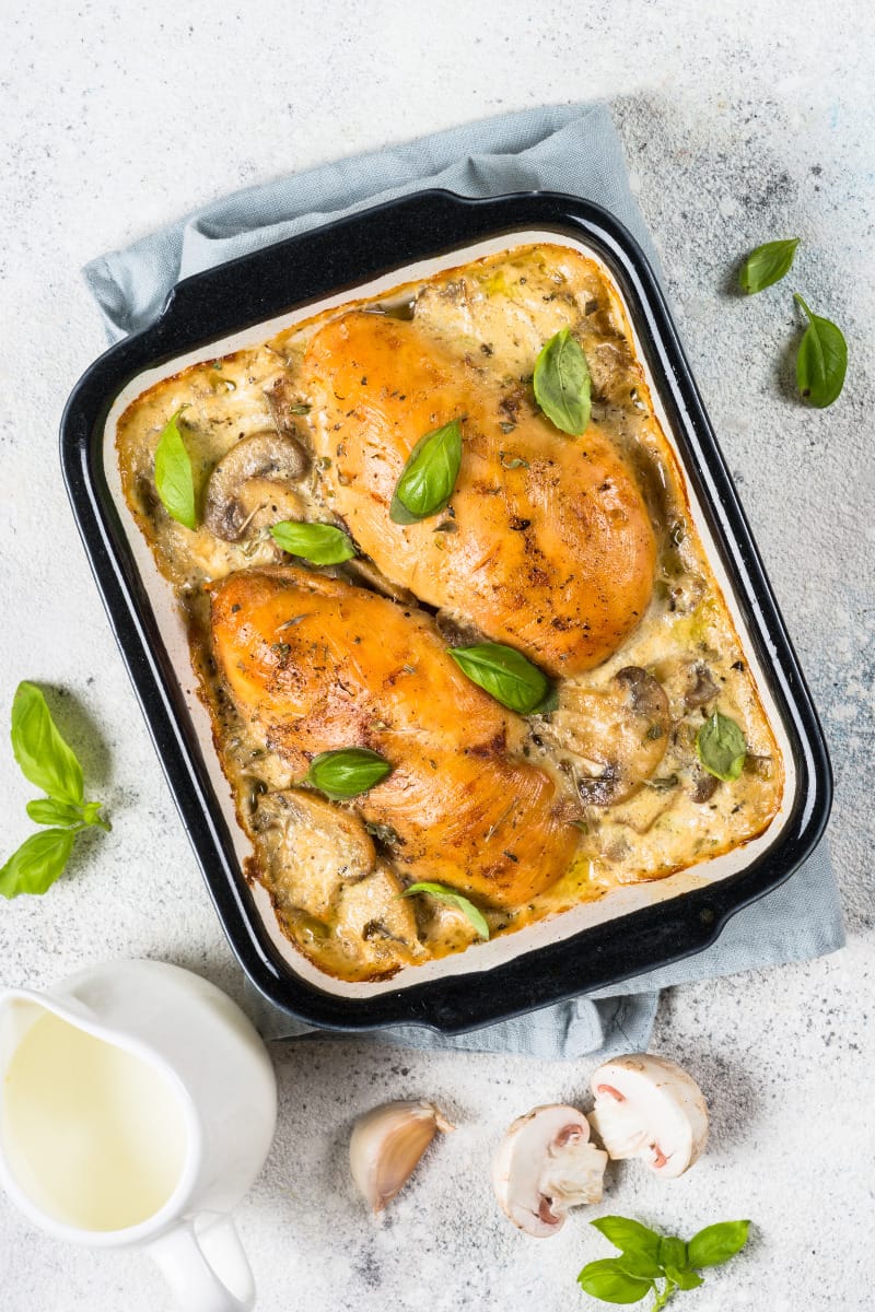 Top view of baked chicken breast in creamy sauce.