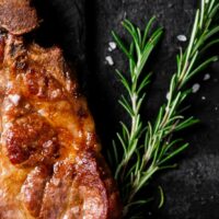 Cooked pork steak with sprig of rosemary.