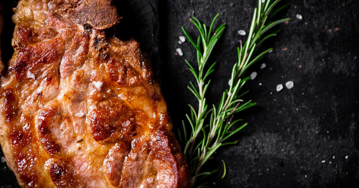 Cooked pork steak with sprig of rosemary.