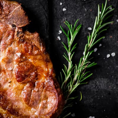 Cooked pork steak with sprig of rosemary.