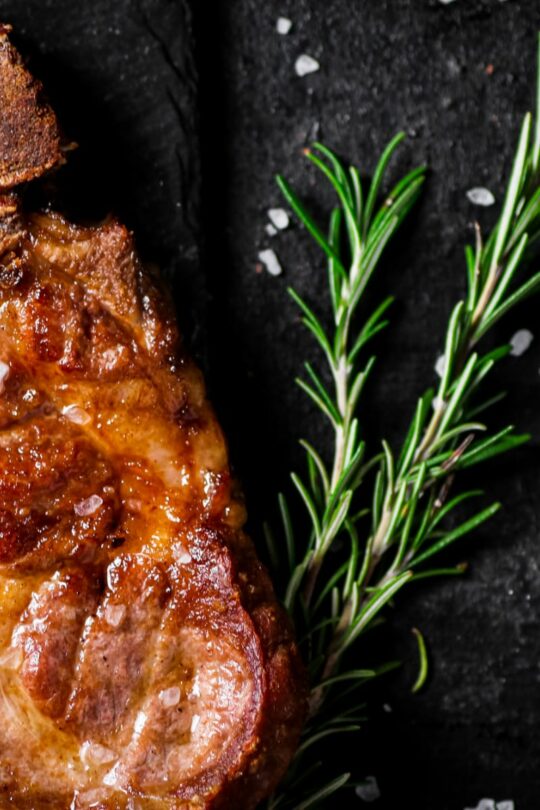 Grilled pork steak with sprig of rosemary.