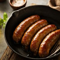 Italian sausage cooked on stove in skillet.