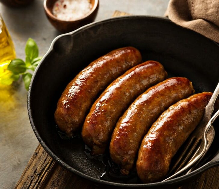 Italian sausage cooked on stove in skillet.