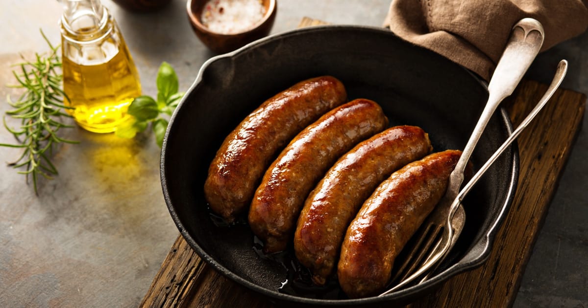 Italian sausage cooked on stove in skillet.