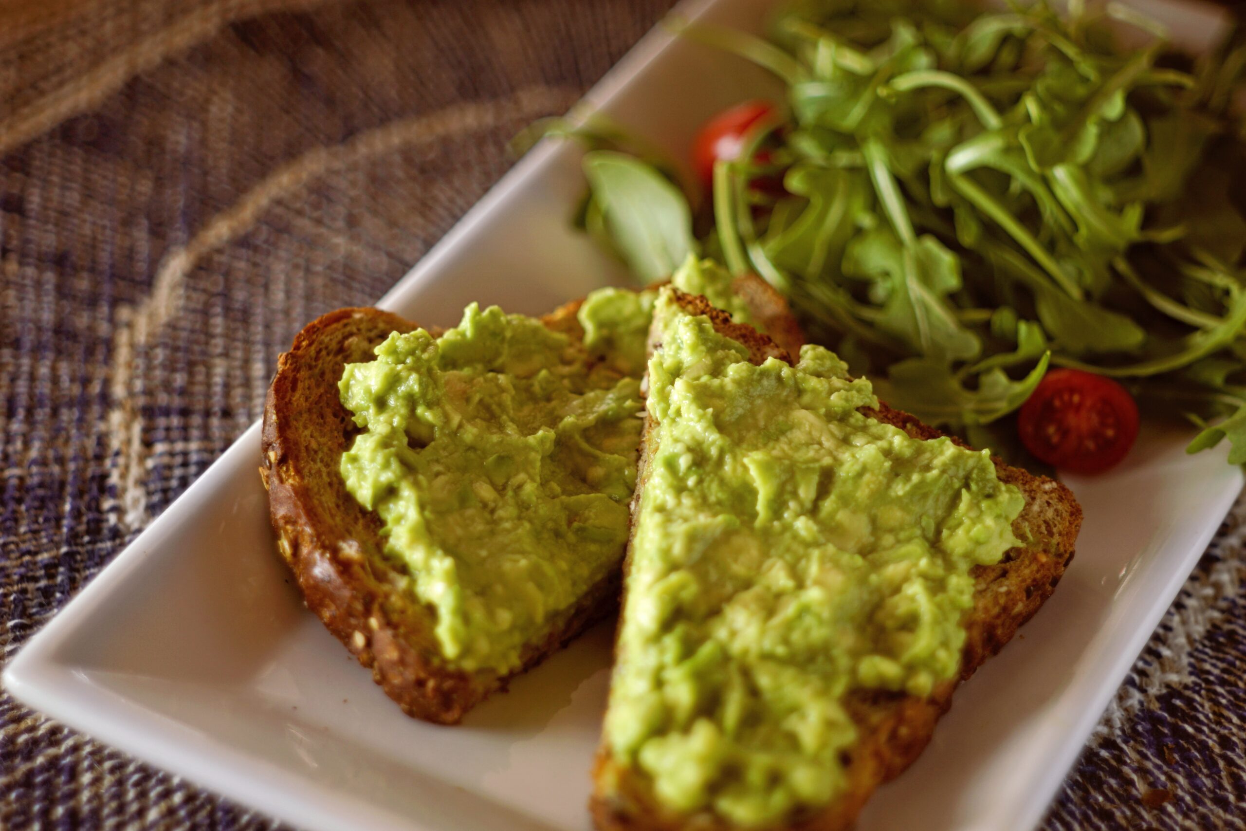 Guacamole on bread toast on white plate