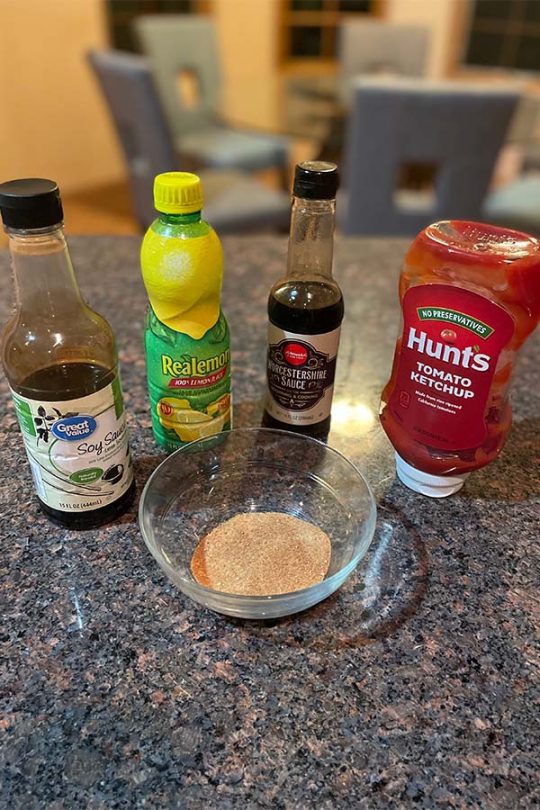 Ketchup, lemon juice, Worcestershire sauce, and soy sauce next to a bowl of brown sugar. 