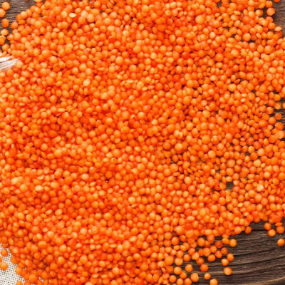 Raw red lentils on wood surface.