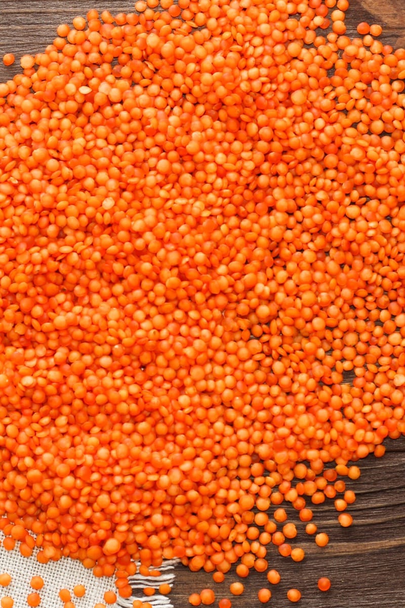 Raw red lentils on wood surface.