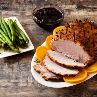 Prepared butt ham on table with side dishes.