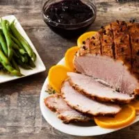 Prepared butt ham on table with side dishes.