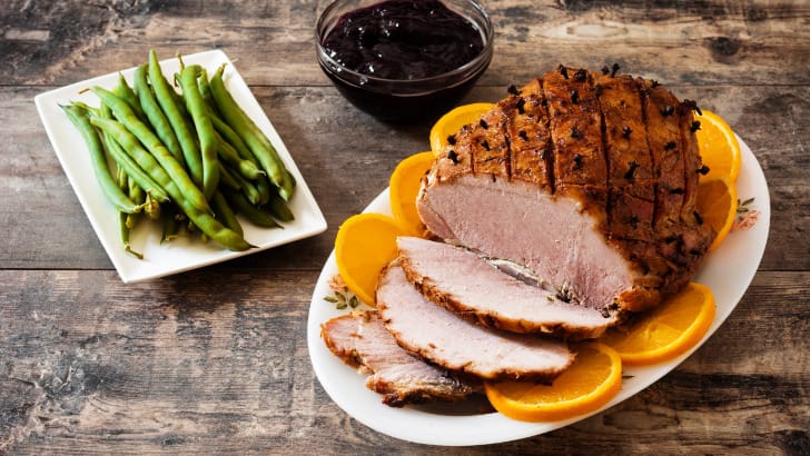 Prepared butt ham on table with side dishes.