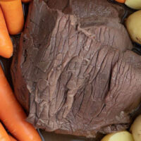 Top view of chuck roast inside Instant Pot with carrots and potatoes.