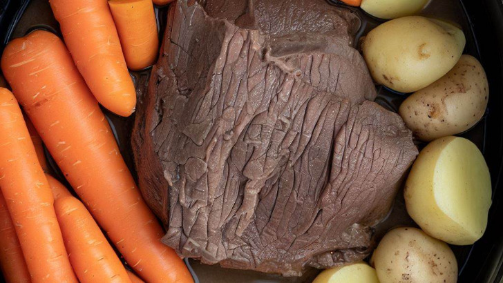 Top view of chuck roast inside Instant Pot with carrots and potatoes.