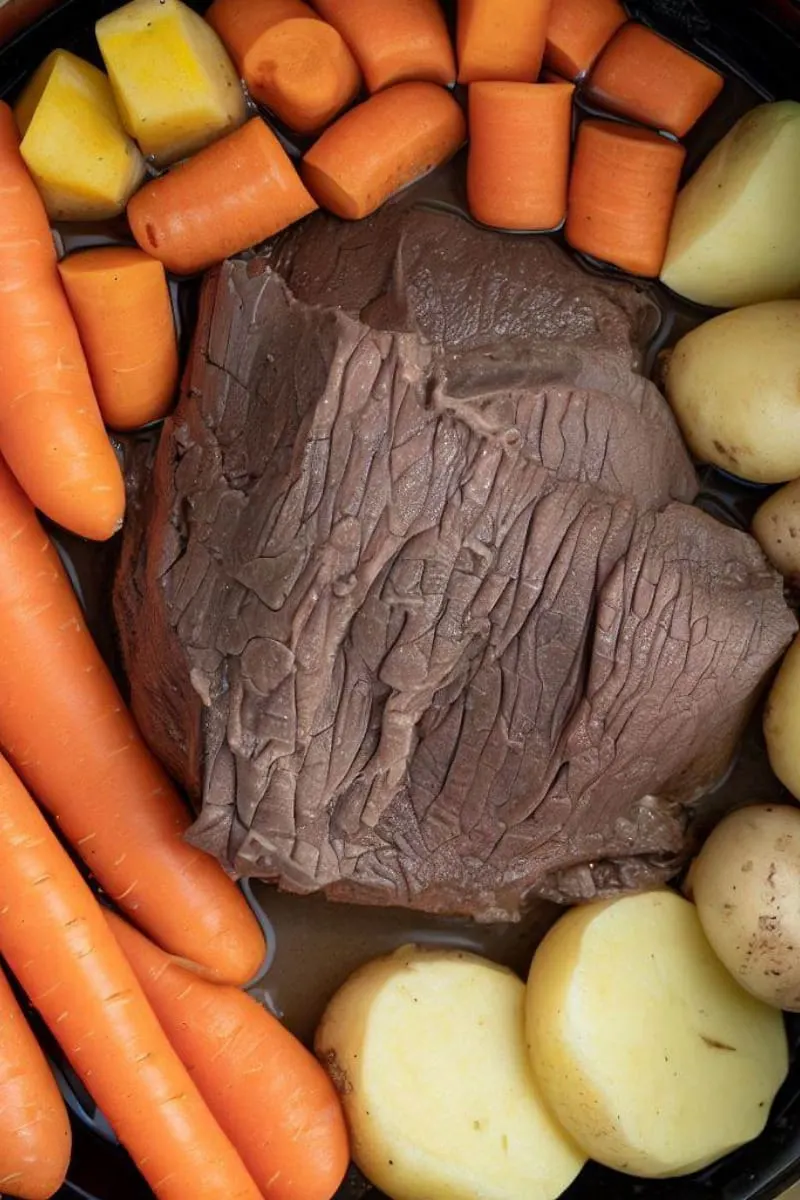 Top view of chuck roast inside Instant Pot with carrots and potatoes.