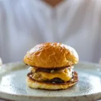 Close-up of woman holding tray with hamburger on it.