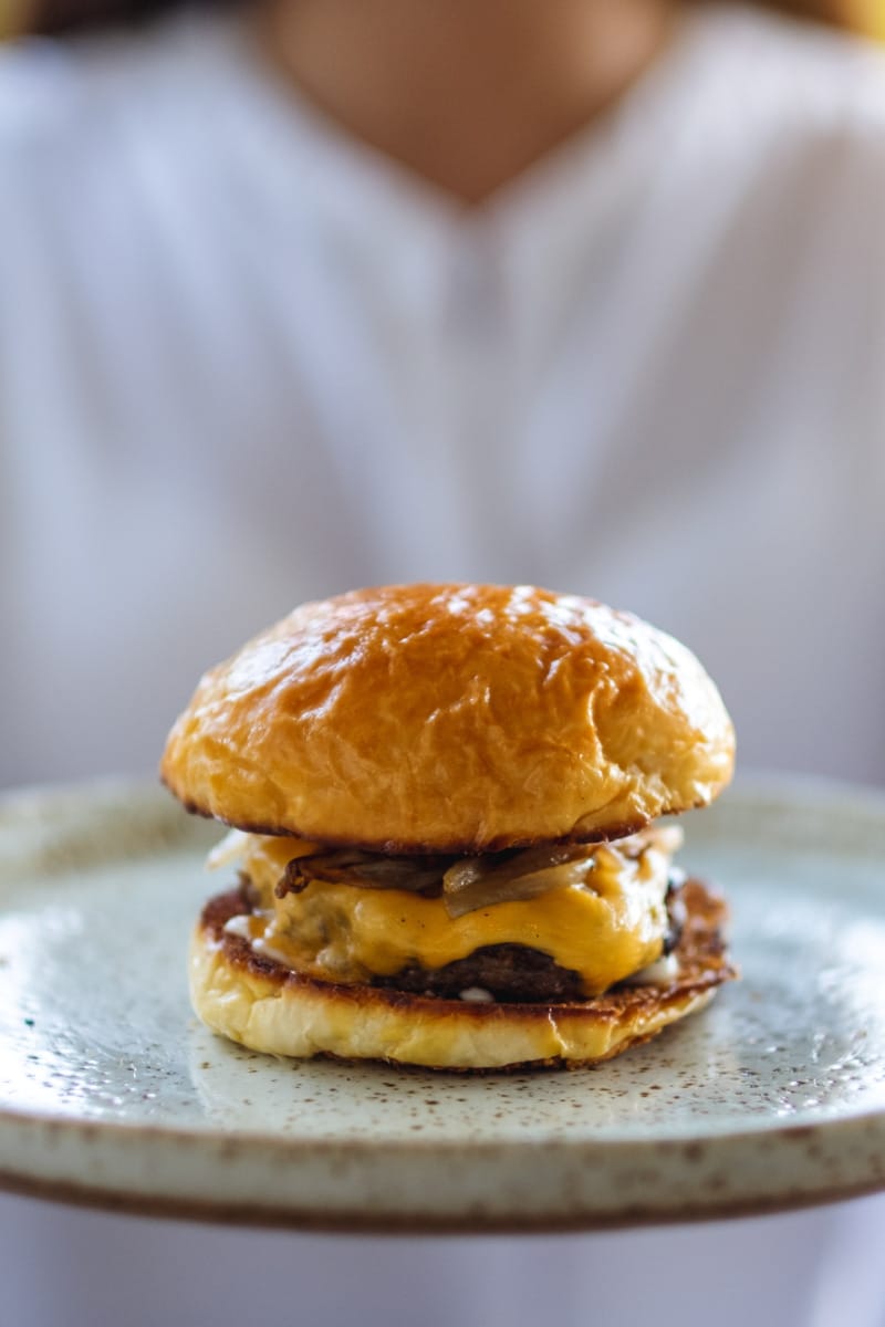 Close-up of woman holding tray with hamburger on it. 