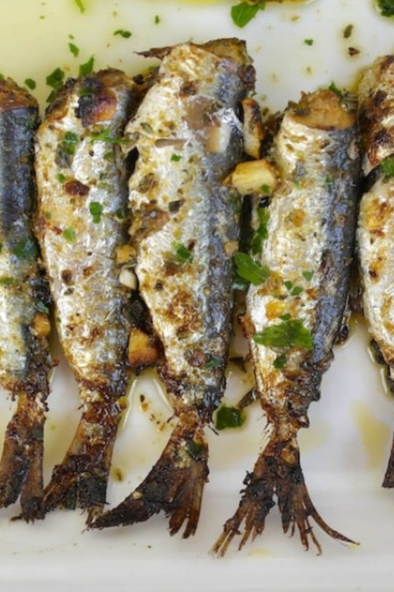 Top view of whole sardines prepared on plate.