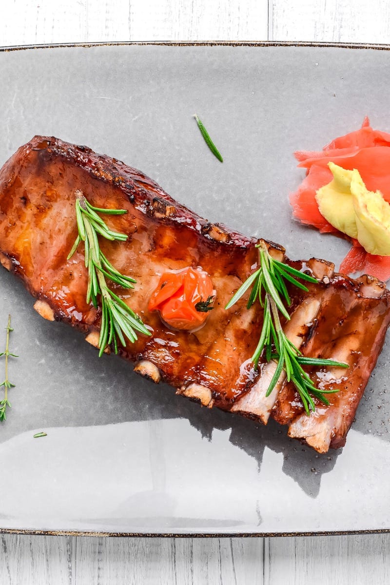 Overhead view of prepared baby back ribs on serving tray. 