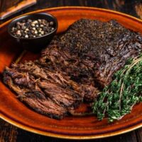 Prepared beef brisket on plate with garnish.