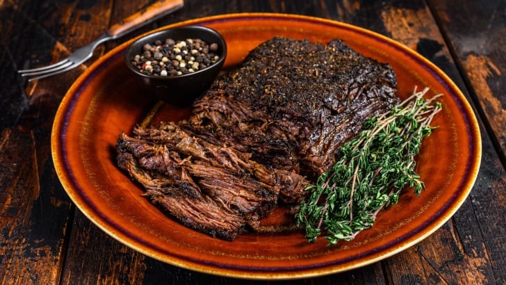 Prepared beef brisket on plate with garnish.