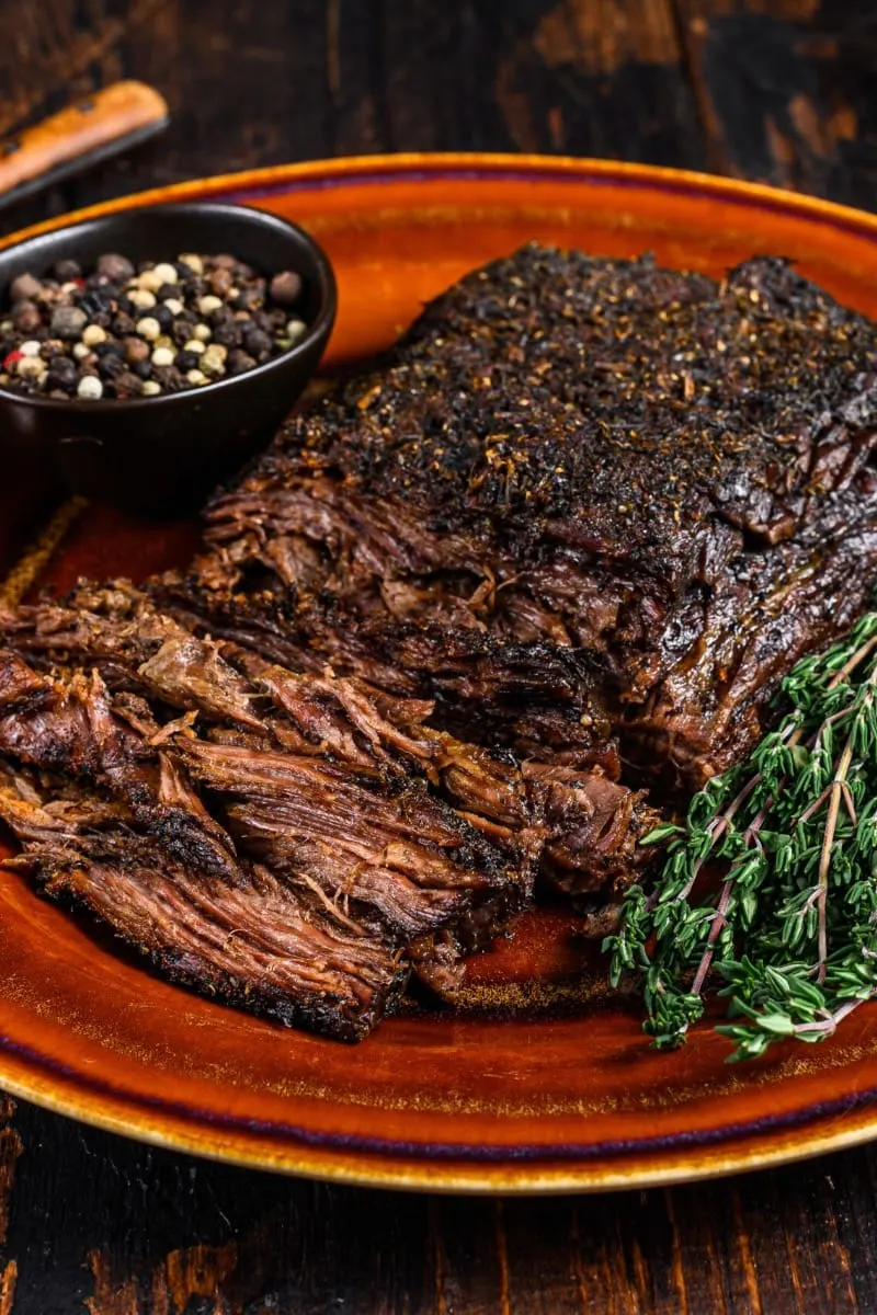 Prepared beef brisket on plate with garnish.