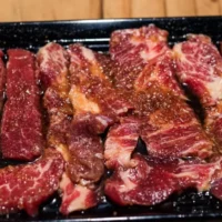 Korean short ribs with marinade on black dish.