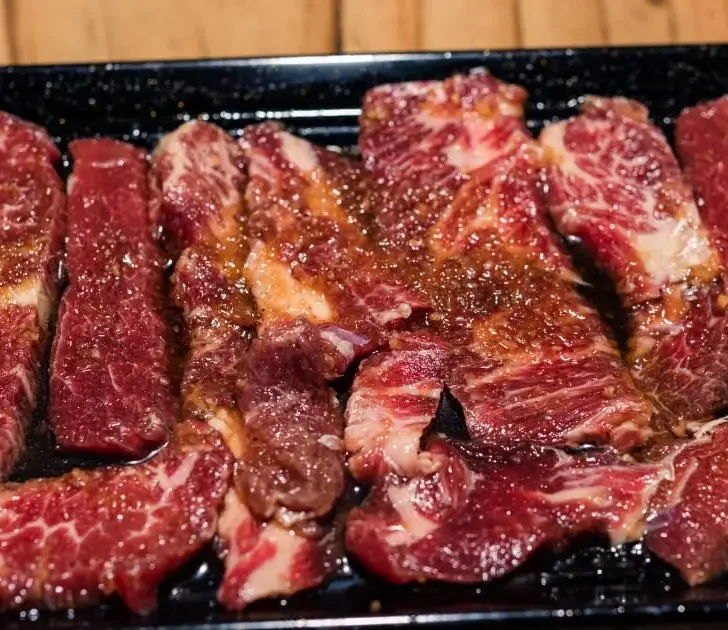 Korean short ribs with marinade on black dish.