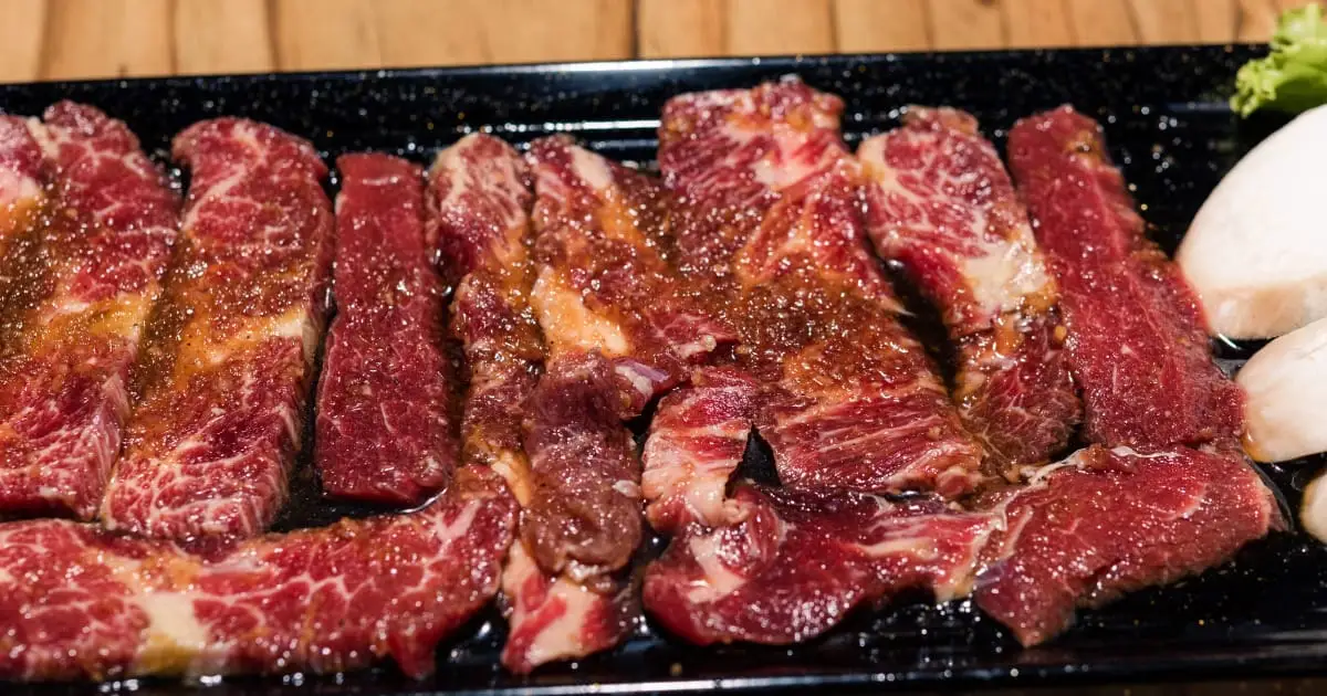 Korean short ribs with marinade on black dish.