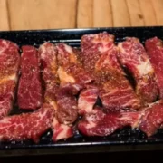 Korean short ribs with marinade on black dish.