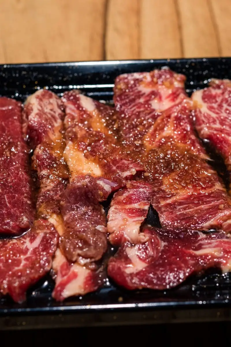 Korean short ribs with marinade on black dish.