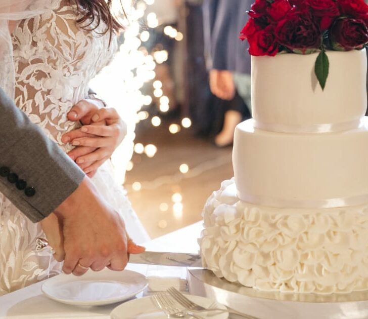 Newly married couple slices wedding cake.