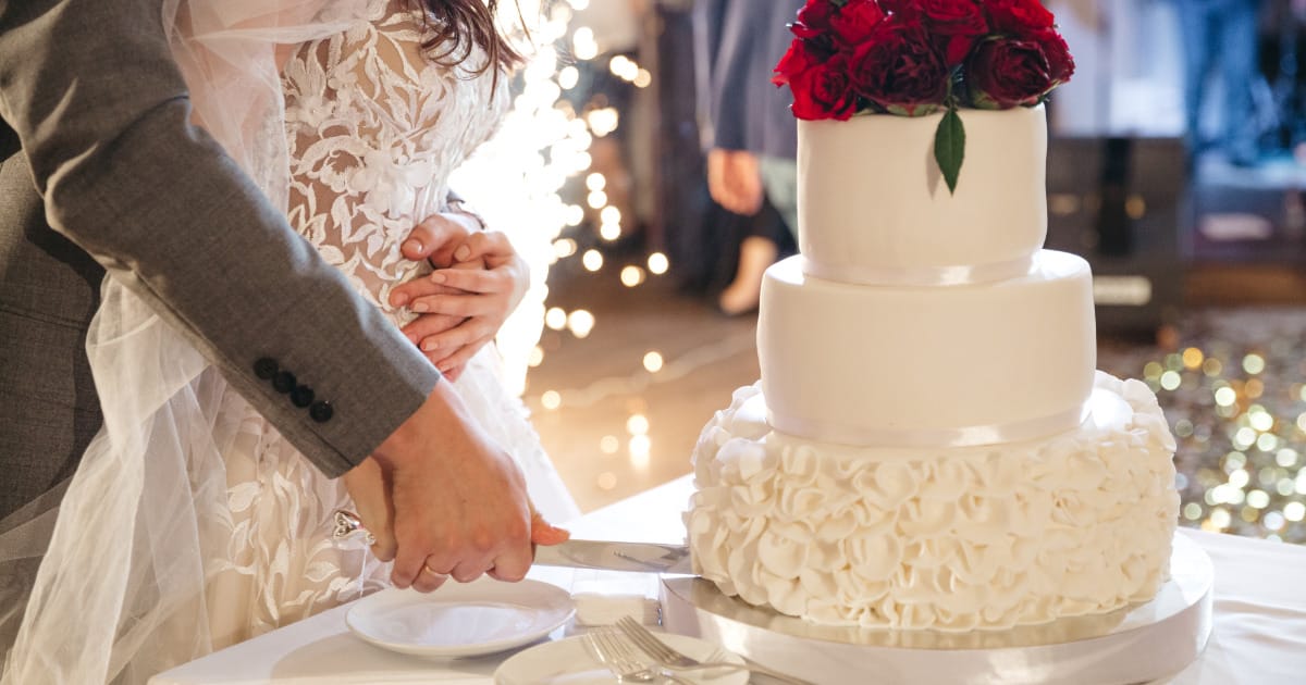 Newly married couple slices wedding cake.