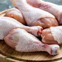 Raw chicken drumsticks on a cutting board.