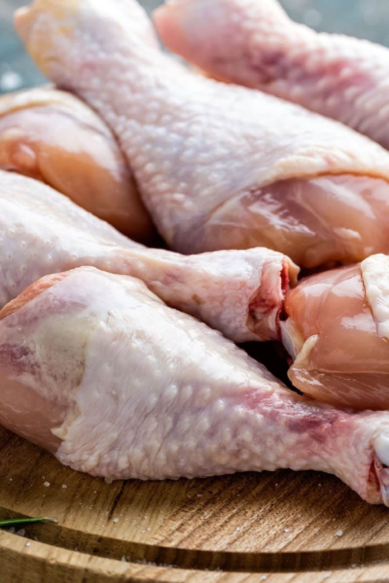 Raw chicken drumsticks on a cutting board.