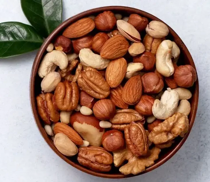 Bowl of mixed nuts on gray background.