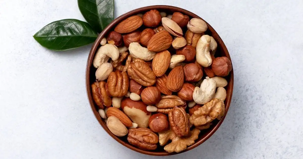 Bowl of mixed nuts on gray background.