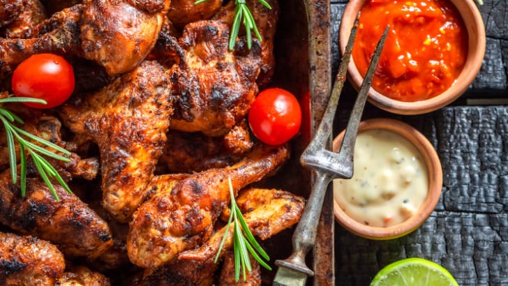 Roasted chicken wings on serving platter with sauces.