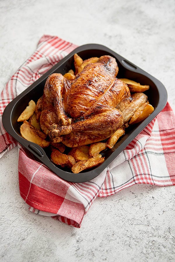 Roasted turkey in black pan with potatoes.