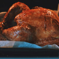 Turkey roasting in pan in oven.