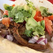 Close up of stovetop carne asada taco with avocado and tomato.