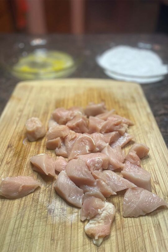 Chicken breast cut into chunks, ready to be coated for cashew chicken.