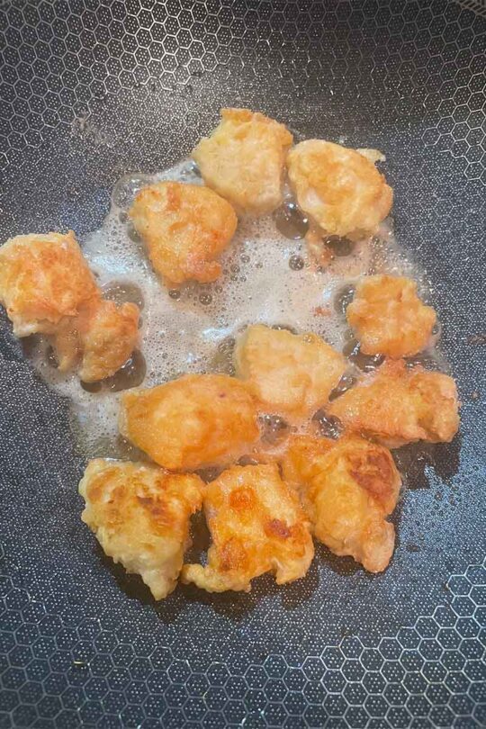 Coated chicken, frying in wok.