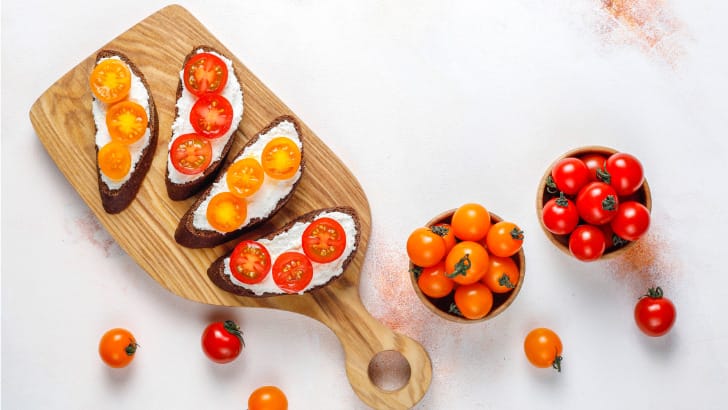 Top view of cherry tomatoes in bowl and sliced on toast.