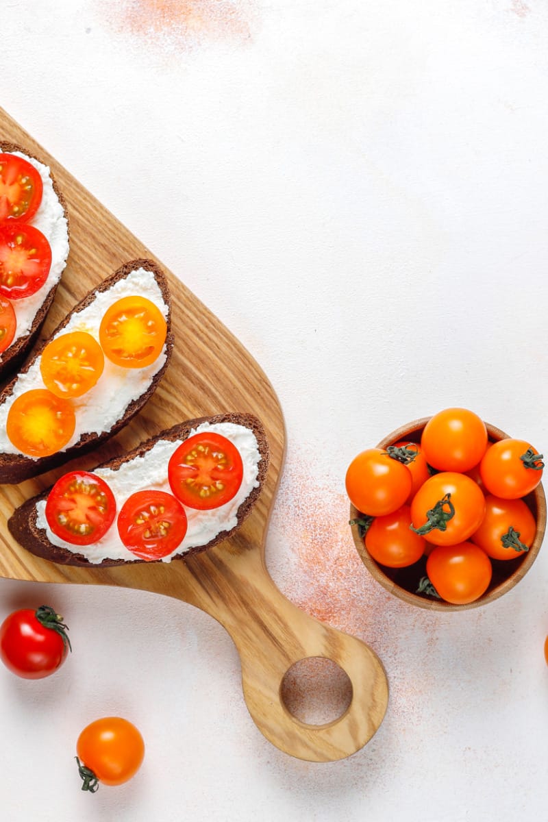 Top view of cherry tomatoes in bowl and sliced on toast.