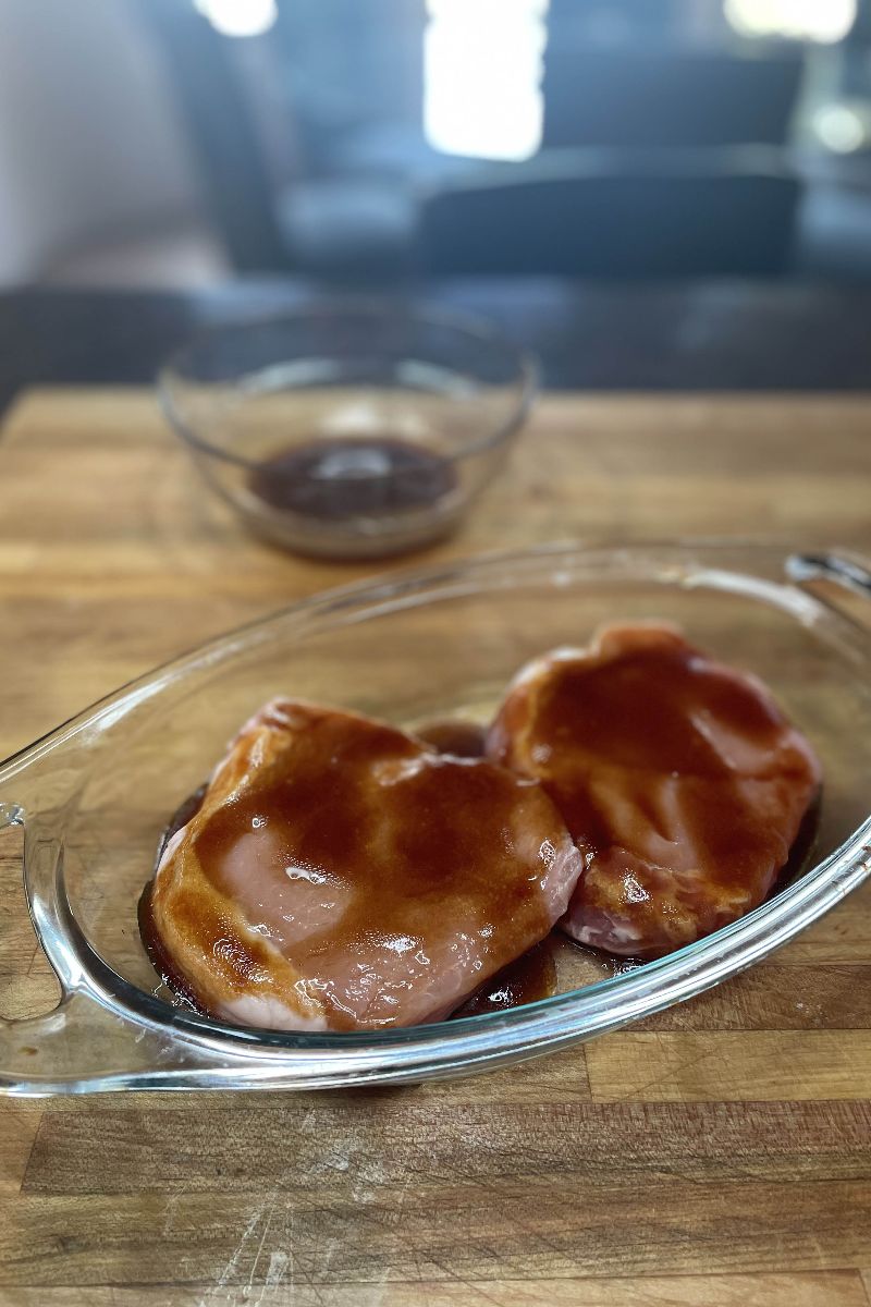 Raw pork loin chops covered with sauce.