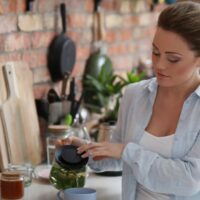 Woman surrounded by eco-friendly kitchen products makes tea.